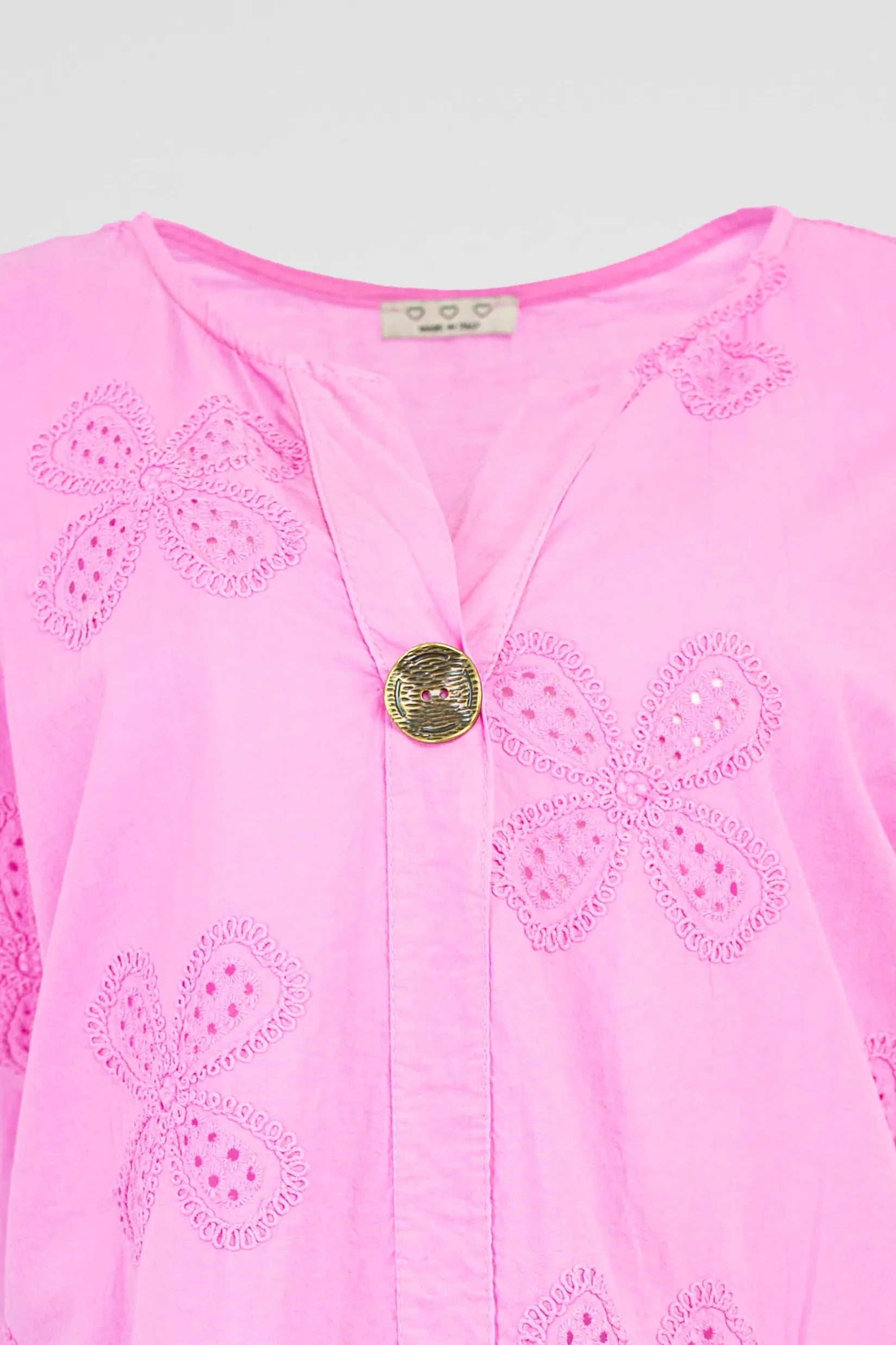 Vibrant pink cotton Bloom Lace shirt with intricate floral eyelet embroidery and a stylish gold button V-neck.