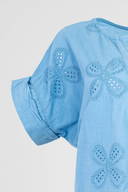 Light blue cotton Bloom Lace blouse with short, rolled sleeves and intricate floral eyelet embroidery.