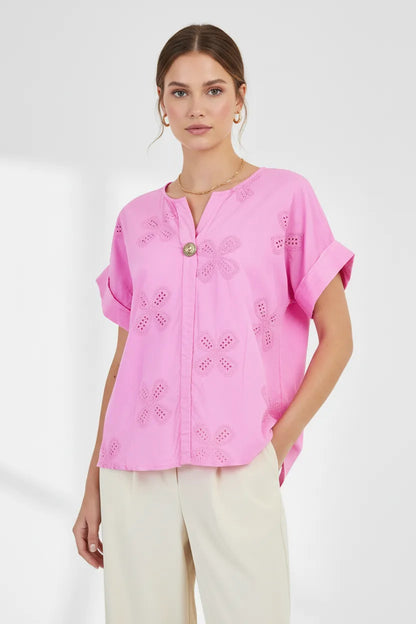 Model wears a vibrant pink Bloom Lace 100% cotton shirt with floral eyelet embroidery, V-neck, and rolled sleeves.