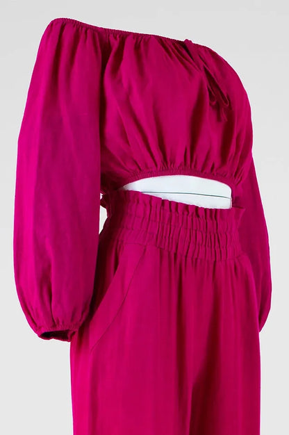 Vibrant fuchsia linen off-shoulder top with voluminous sleeves and high-waisted pants, perfect for summer.