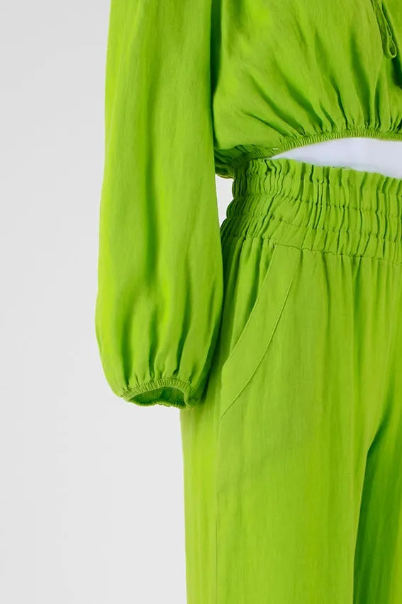 Vibrant green linen two-piece set featuring an off-shoulder top and high-waisted pants with elastic details.