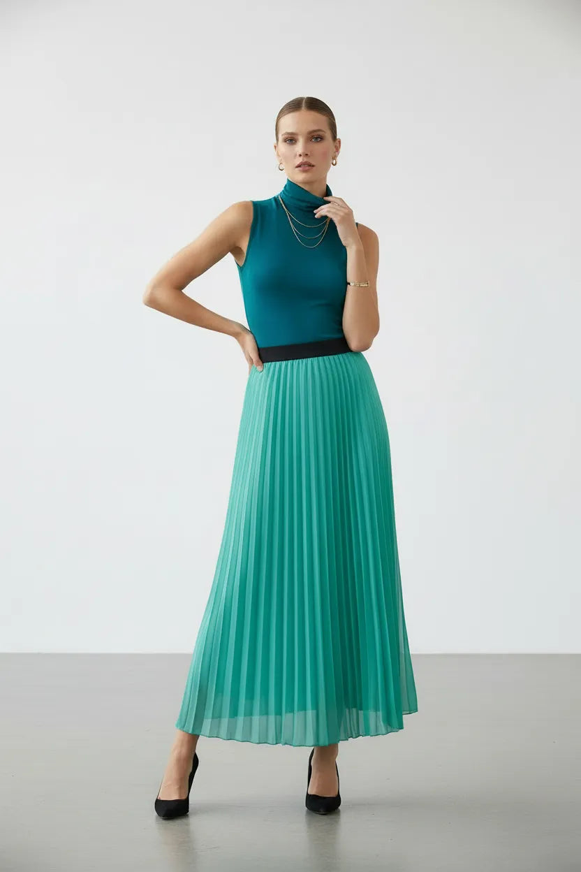 Elegant model in a flowing mint green pleated maxi skirt with a chic black elastic waistband.