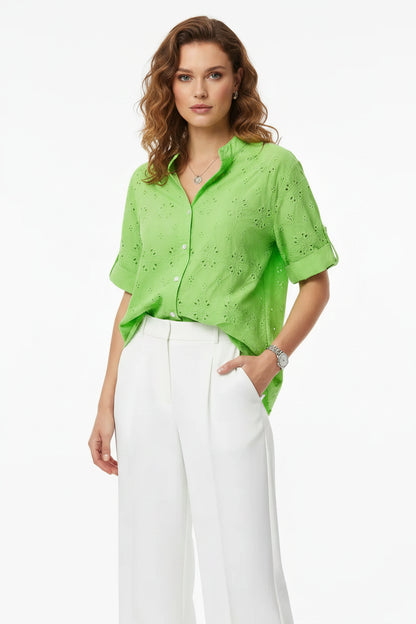 Vibrant green cotton shirt with embroidered lace details, V-neck, short sleeves, paired with white wide-leg pants.