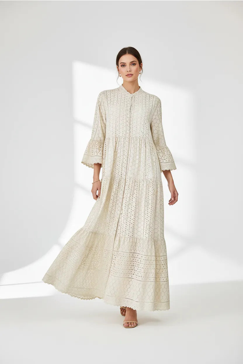 Elegant beige 100% cotton maxi dress with intricate eyelet embroidery, tiered skirt, and flared sleeves.