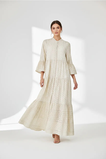 Elegant beige 100% cotton maxi dress with intricate eyelet embroidery, tiered skirt, and flared sleeves.