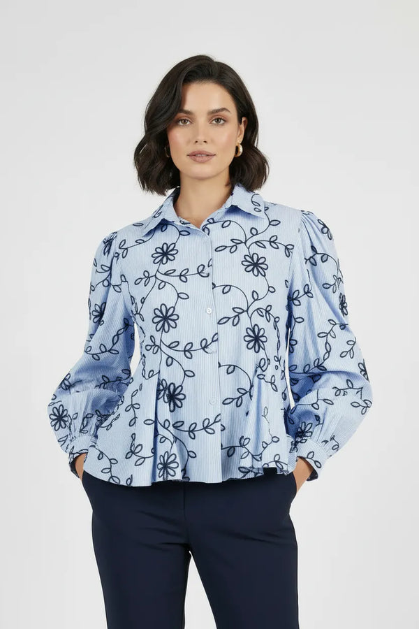 Дамска светлосиня раирана риза с тъмносиня флорална бродерия, обемни ръкави и пеплум кройка.