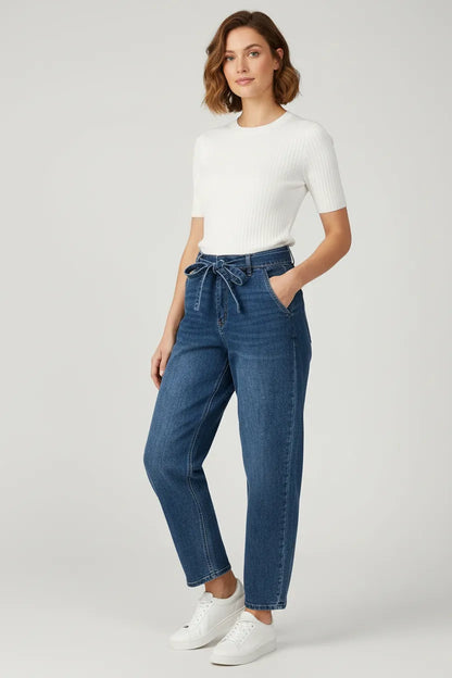 Stylish woman in high-waisted blue denim jeans with a tie belt, paired with a white ribbed top.