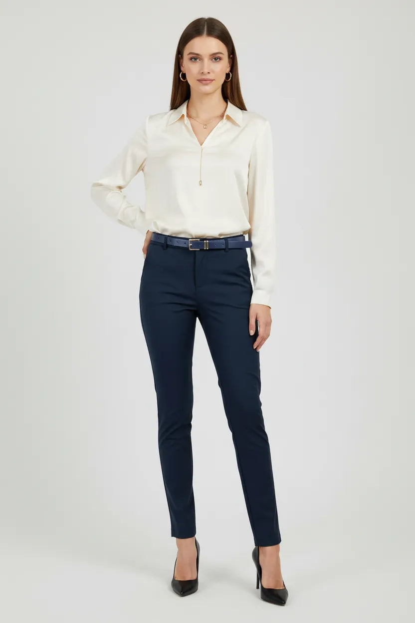Elegant woman in dark blue Diana straight-leg pants with a belt, paired with a cream blouse and heels.