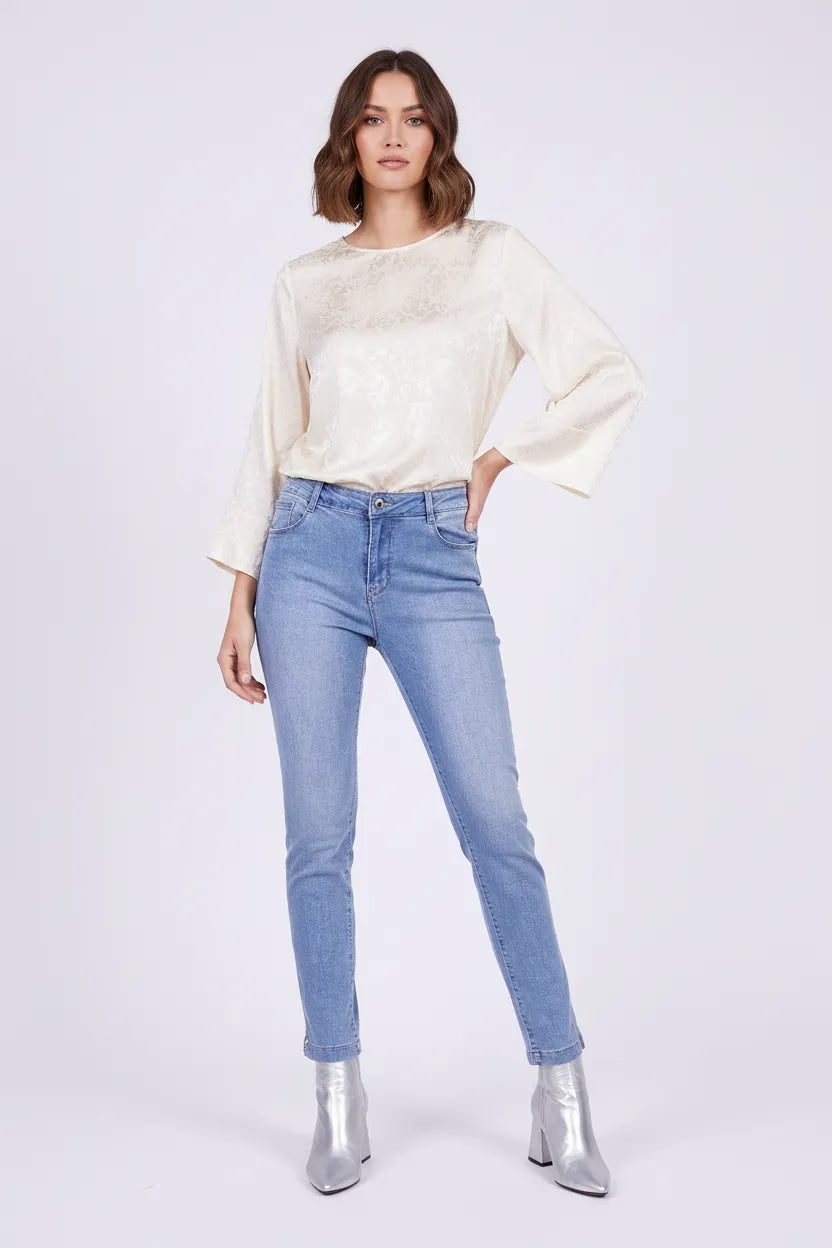 Stylish woman in medium wash slim-fit high-waisted plus size jeans and an elegant cream blouse.