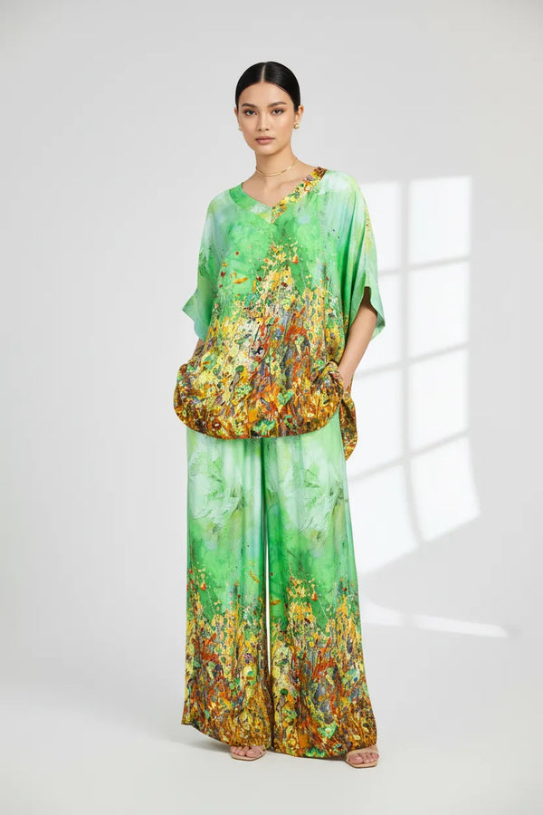 Дамски копринен сет Aurora Muse: топ с V-деколте и широк панталон с артистичен принт в зелено, жълто и оранжево.