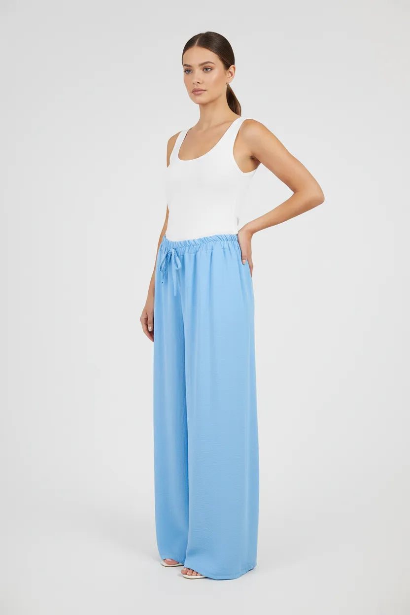 Model wears Sky Flow light blue wide-leg summer pants with elastic waist and drawstring.