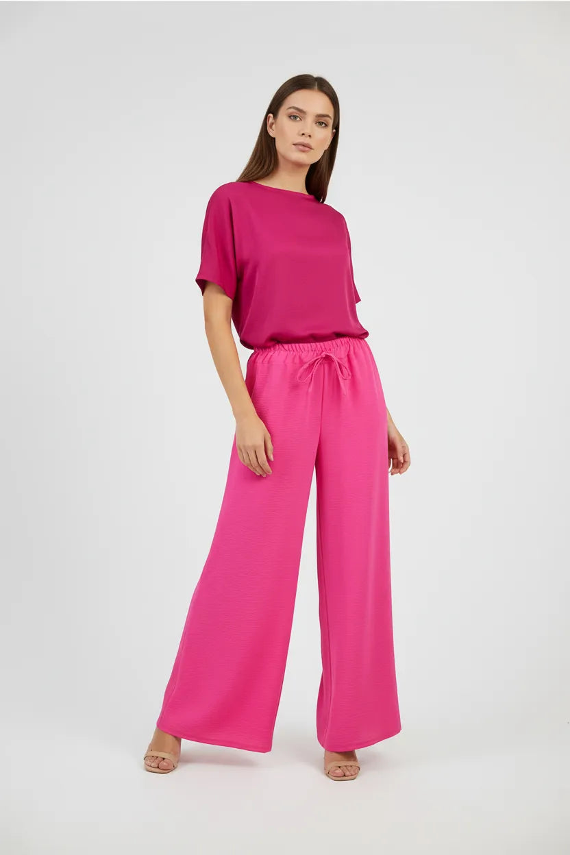 Stylish woman in a vibrant pink wide-leg summer pant and matching top, perfect for comfort and style.