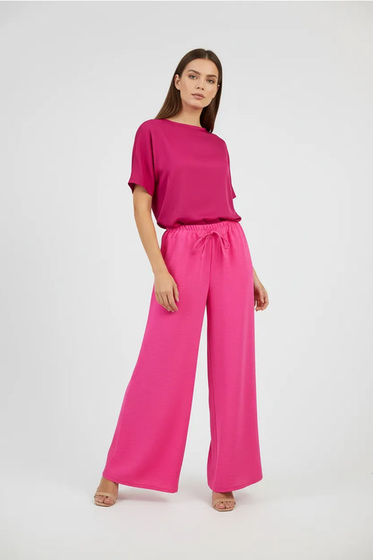 Stylish woman in a vibrant pink wide-leg summer pant and matching top, perfect for comfort and style.