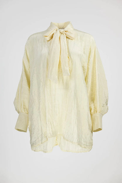 Елегантна блуза от 100% полиестер в цвят ванилия с панделка на яката и обемни ръкави.