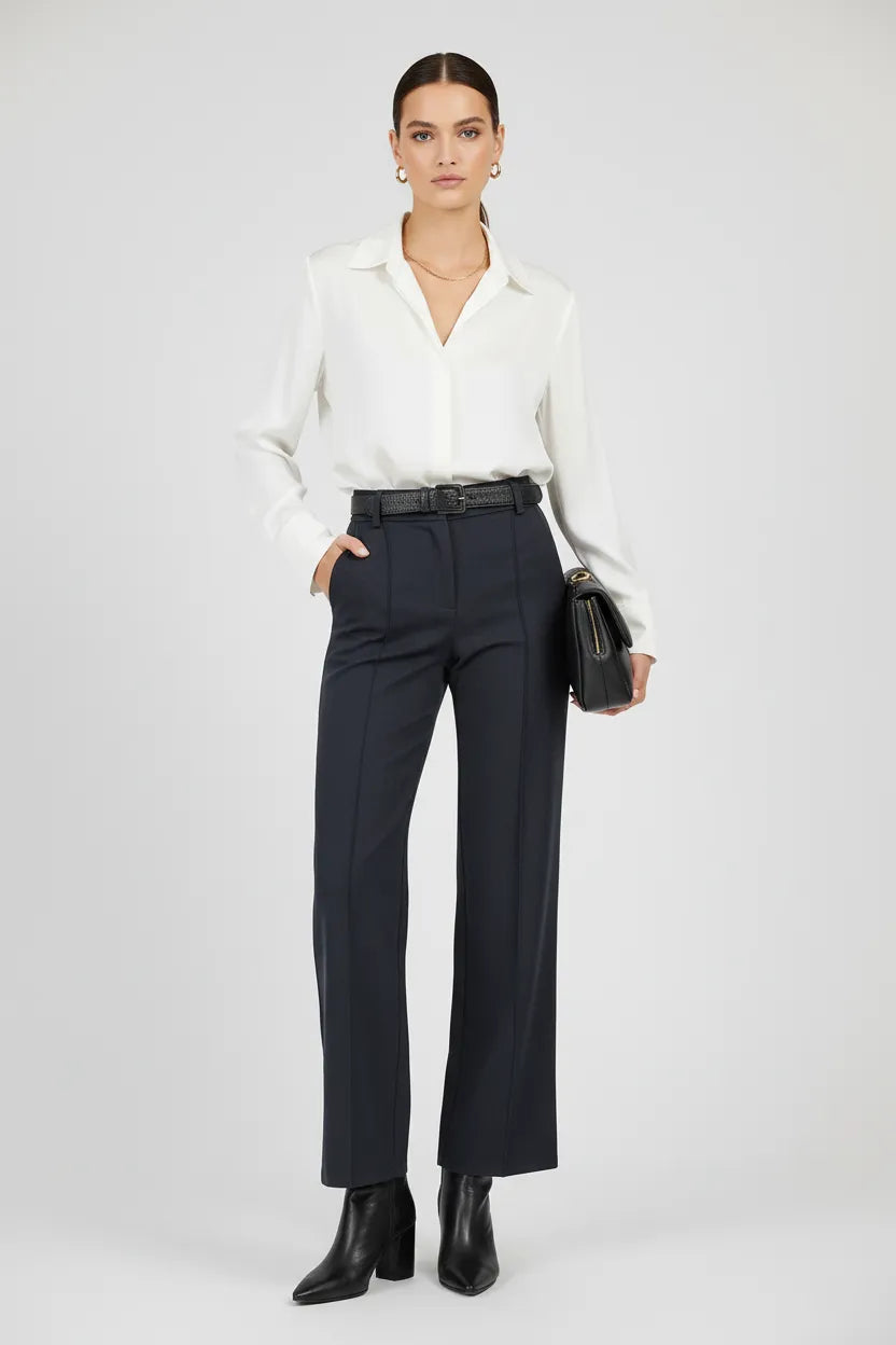 Elegant model wears Sense black straight-leg trousers with decorative seams, a white shirt, and black boots.