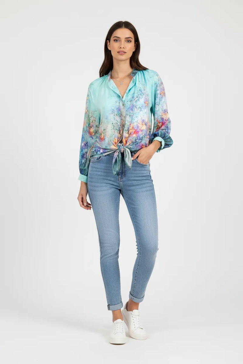 Модерна визия: жена носи тюркоазена копринена риза с акварелен принт и светли скини деним дънки.